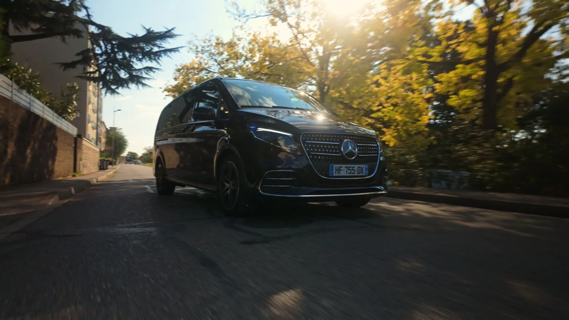 Van Mercedes Classe V noir en mouvement dans une rue, lumière dorée