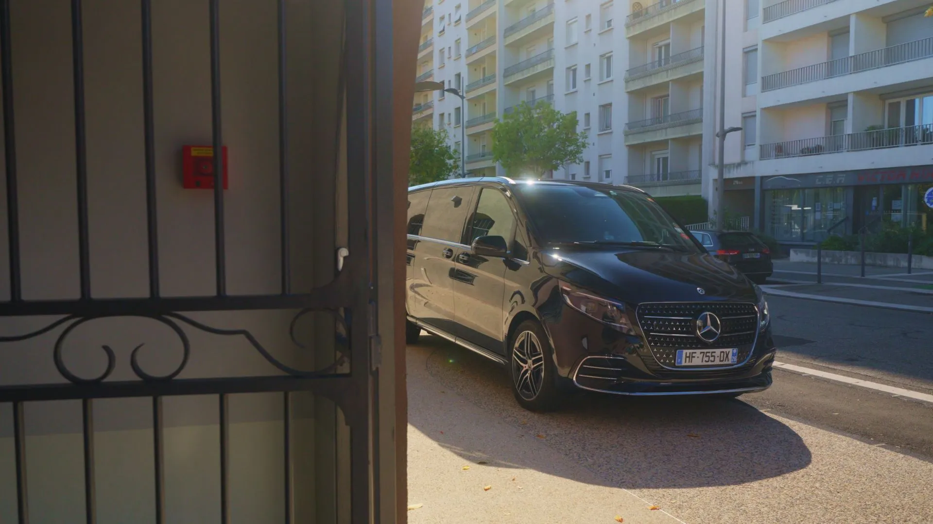Van noir stationné en ville devant un portail