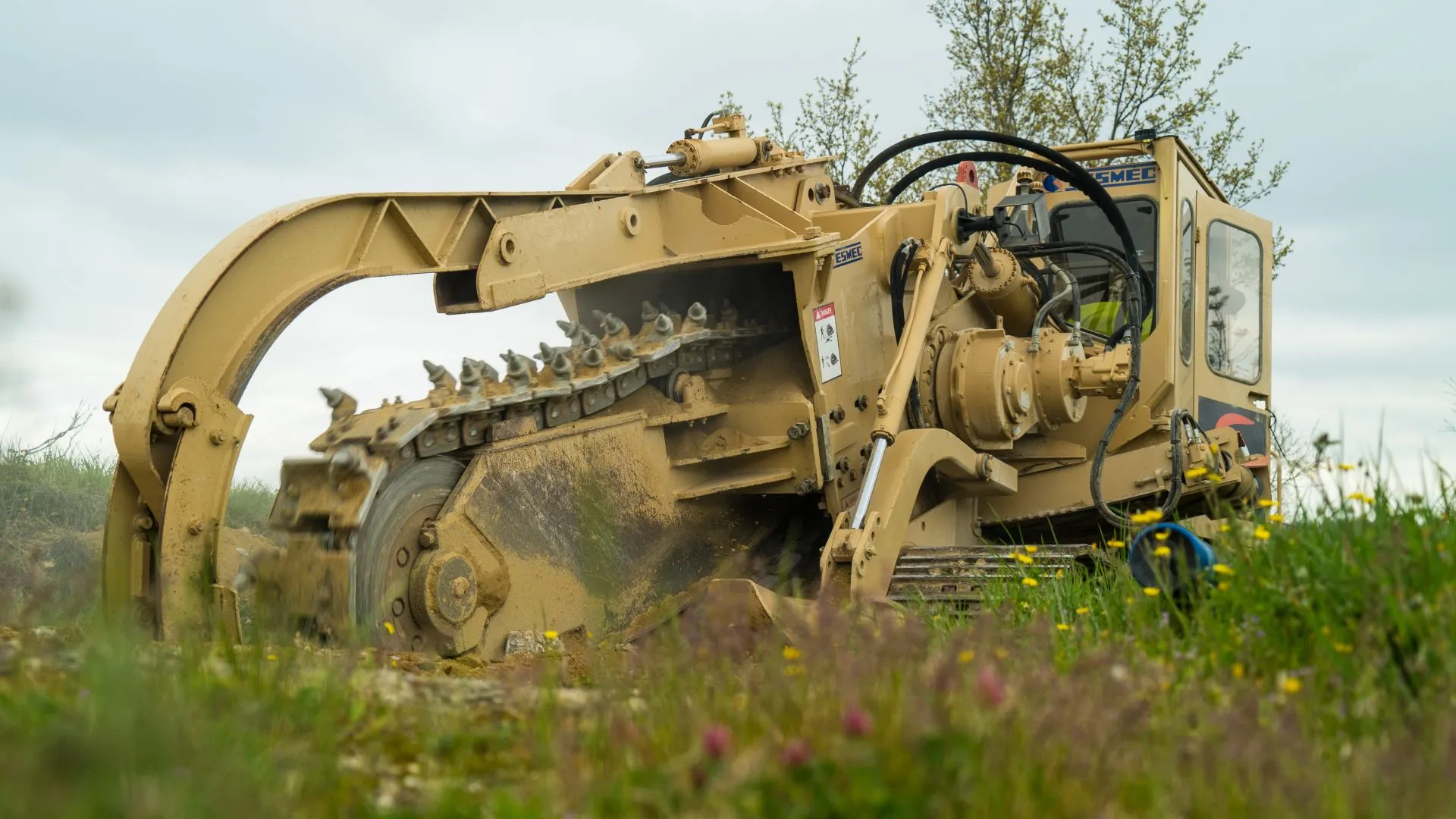Trancheuse au travail dans l'herbe, chantier de réseaux