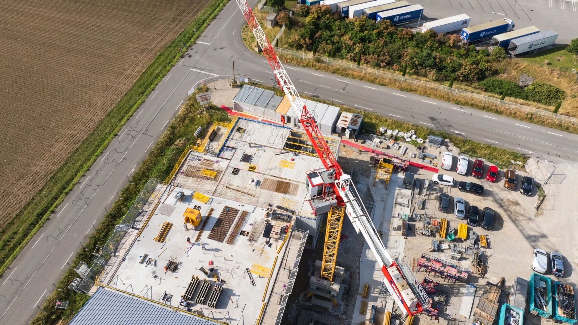 Vue aérienne d'un chantier avec grue rouge et zone de stockage