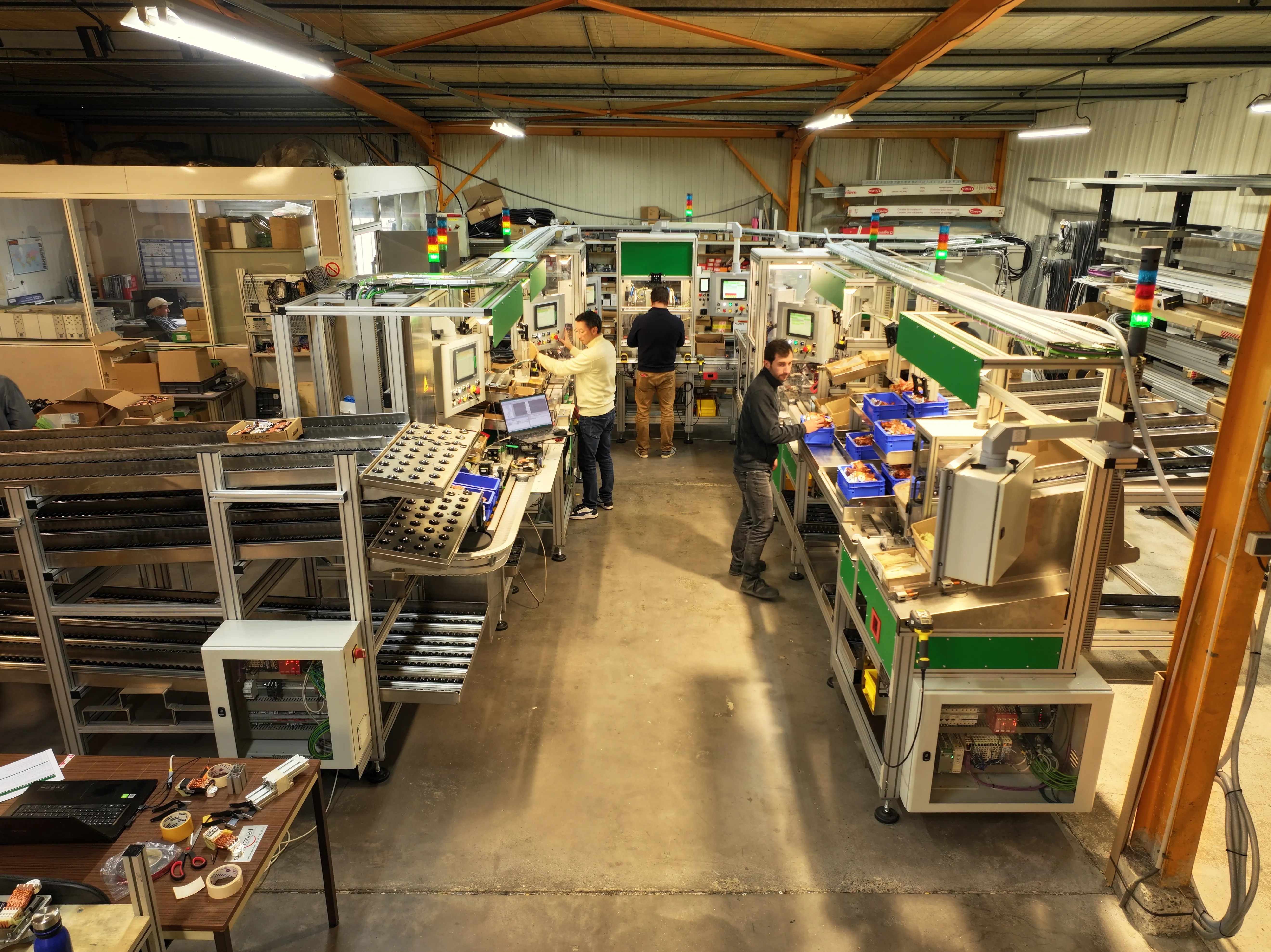 Ligne d'assemblage automatisée ERMOVAL en atelier, sept postes en U avec convoyeur et opérateurs