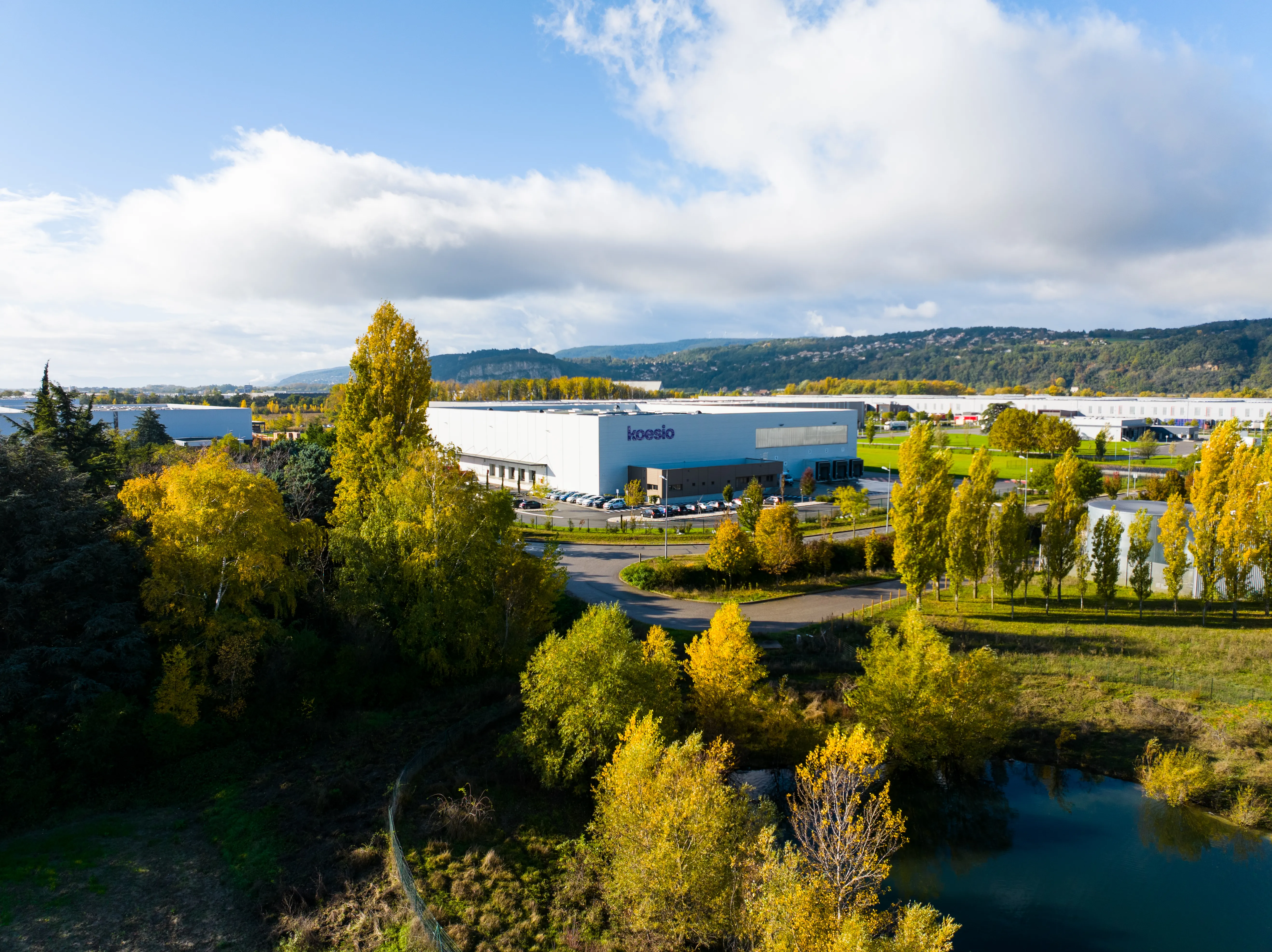 Vue aérienne du centre EOLE KOESIO à Valence, bâtiment blanc aux quais de chargement entouré de végétation automnale