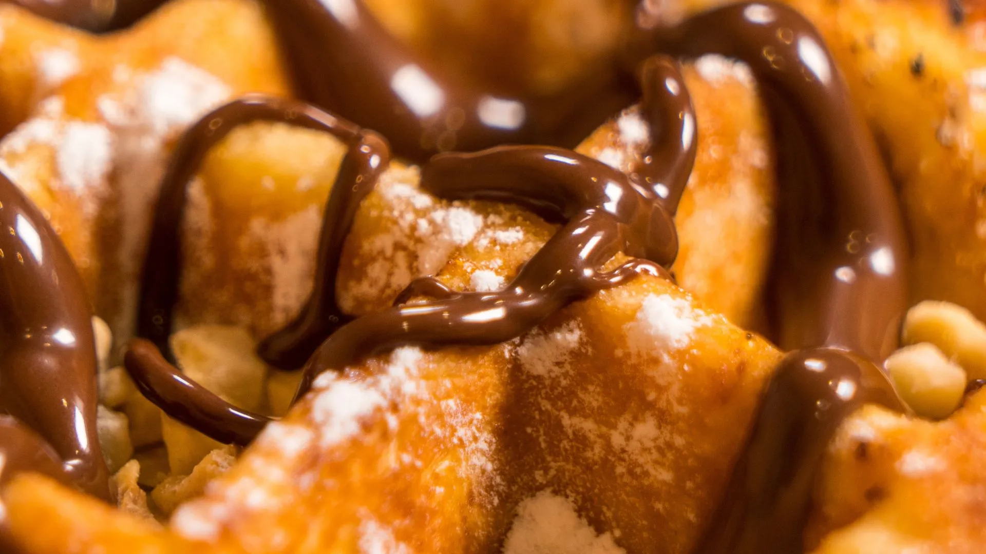 Gros plan gourmand sur une pâtisserie nappée de chocolat et noisettes