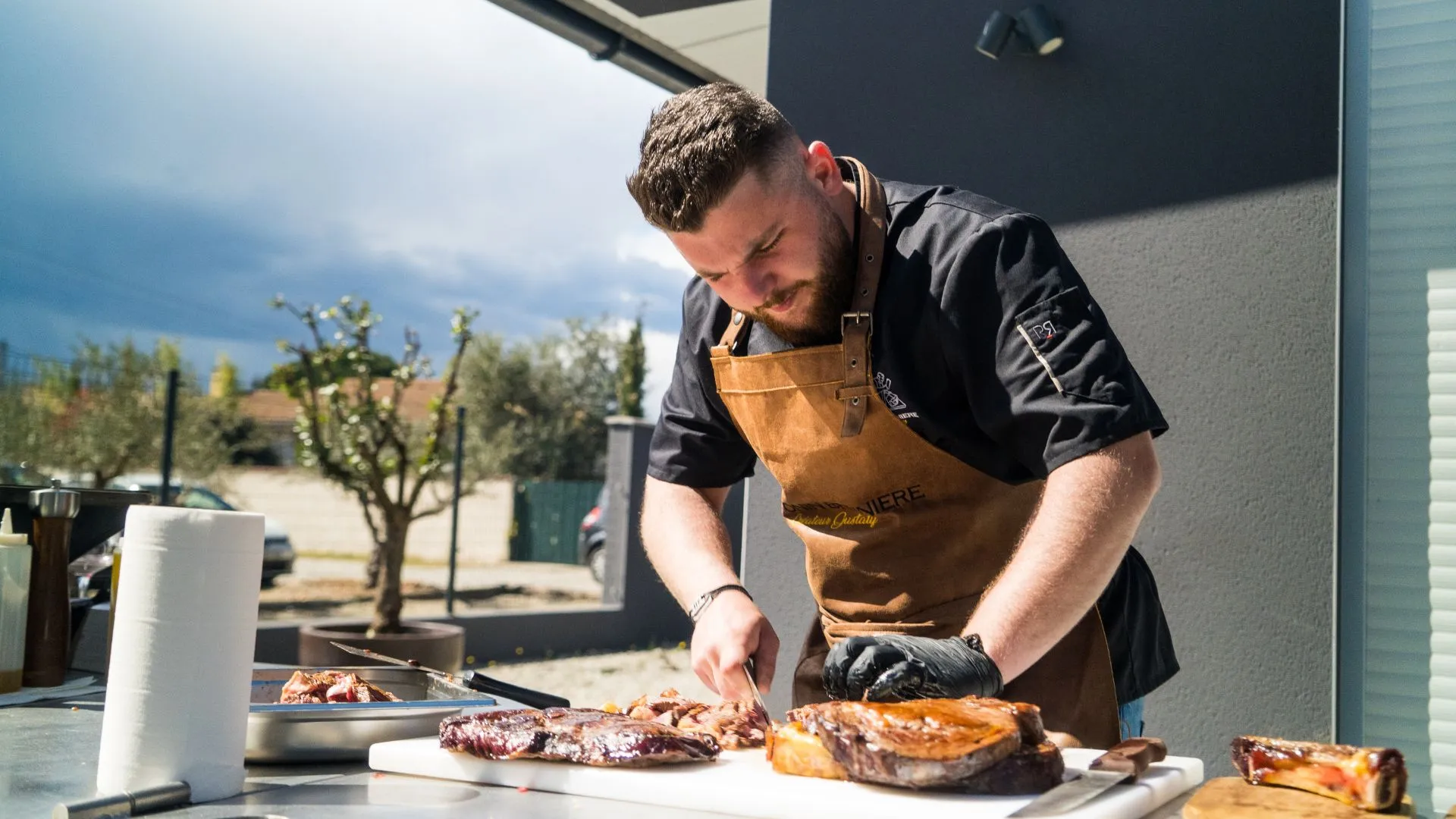 Chef découpant une pièce de viande à la plancha en extérieur