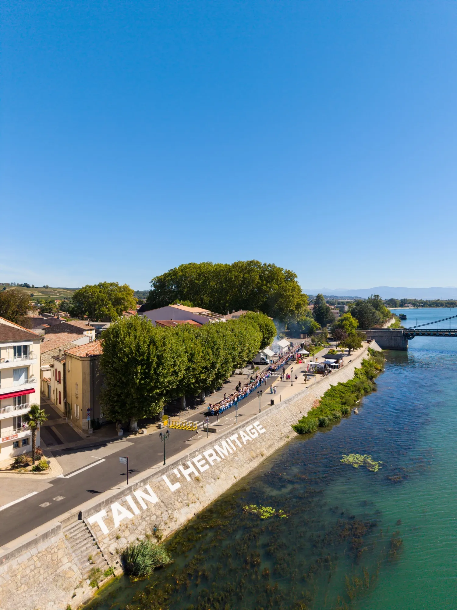 Vue drone rapprochée de la tablée XXL et des convives au bord du Rhône