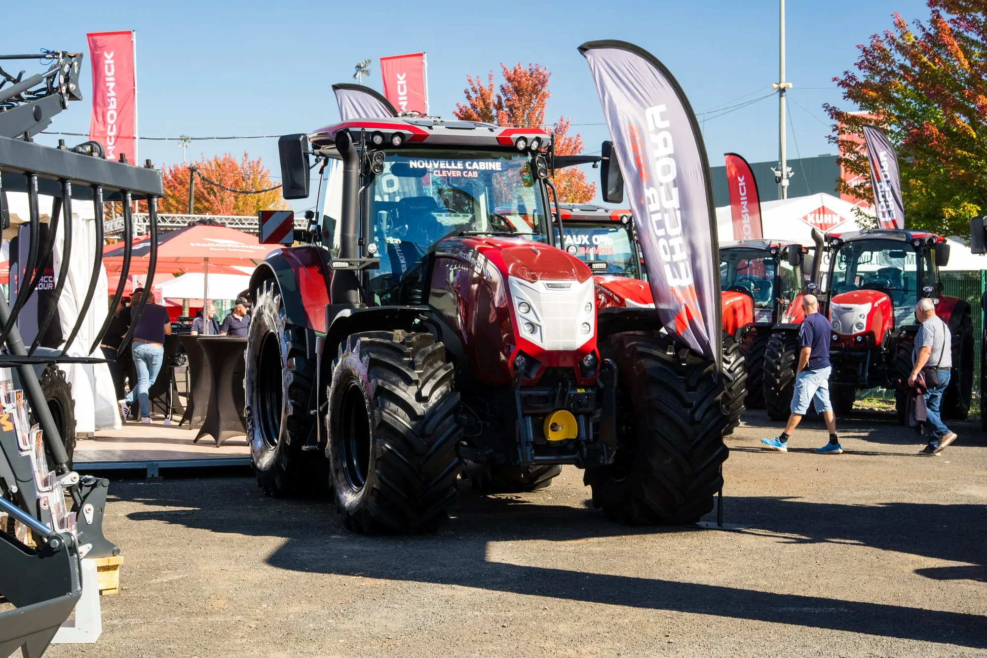 Tracteur McCormick de face sur le stand, oriflammes rouges et visiteurs en arrière-plan