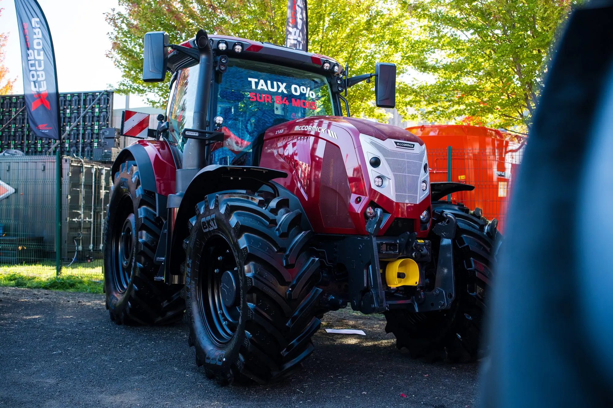 Tracteur McCormick de trois quarts sur le stand, feuillage d'automne en arrière-plan
