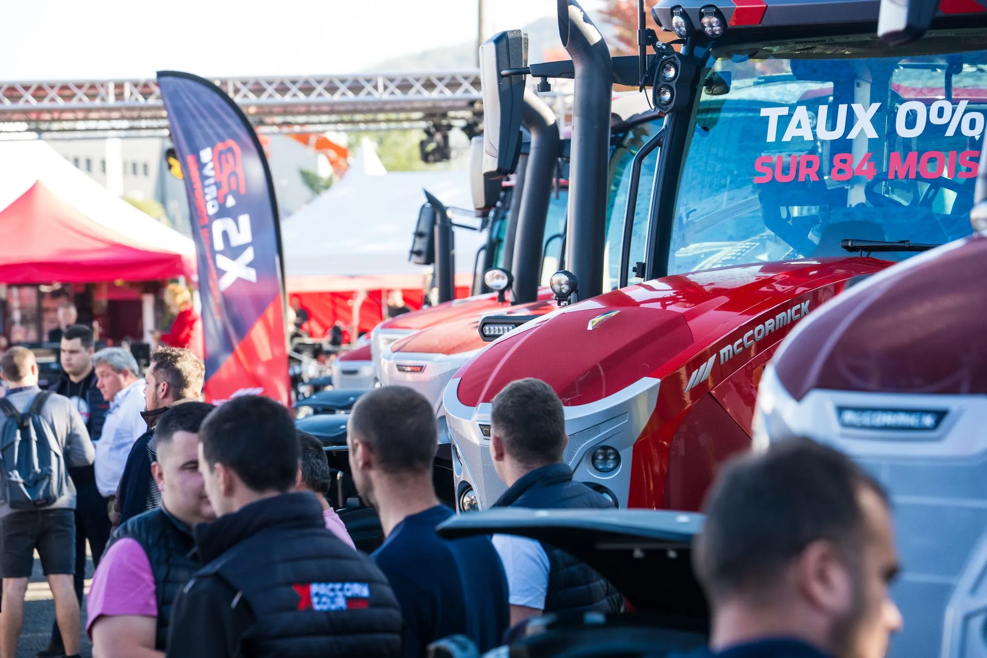 Visiteurs autour des tracteurs McCormick sur le stand, offre de financement affichée sur le pare-brise