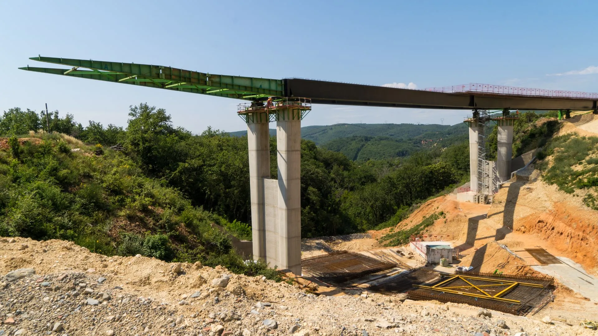 Viaduc en construction, piles en béton et tabliers métalliques au-dessus de la vallée