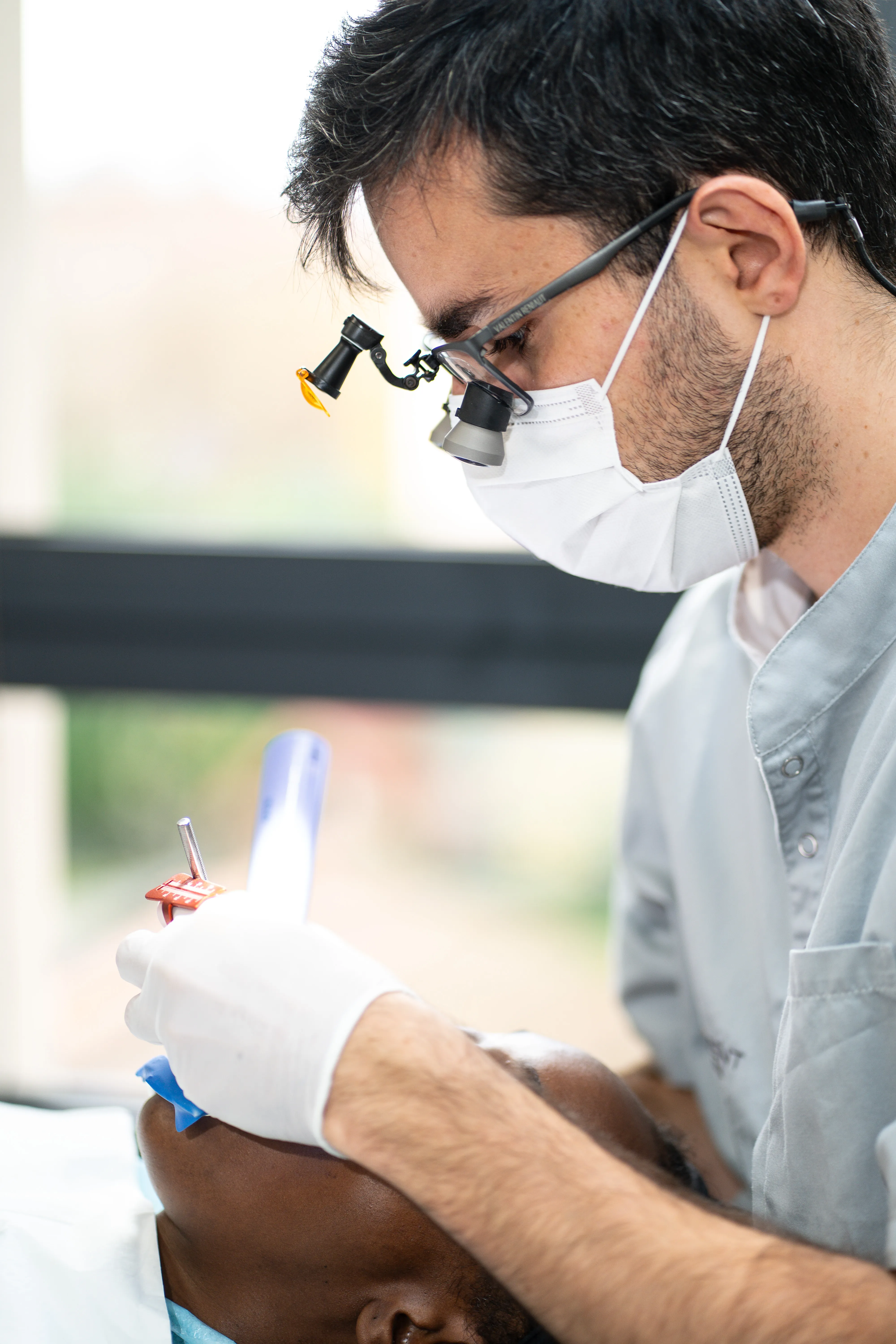 Dentiste en loupes opérant sur un patient isolé avec digue dentaire