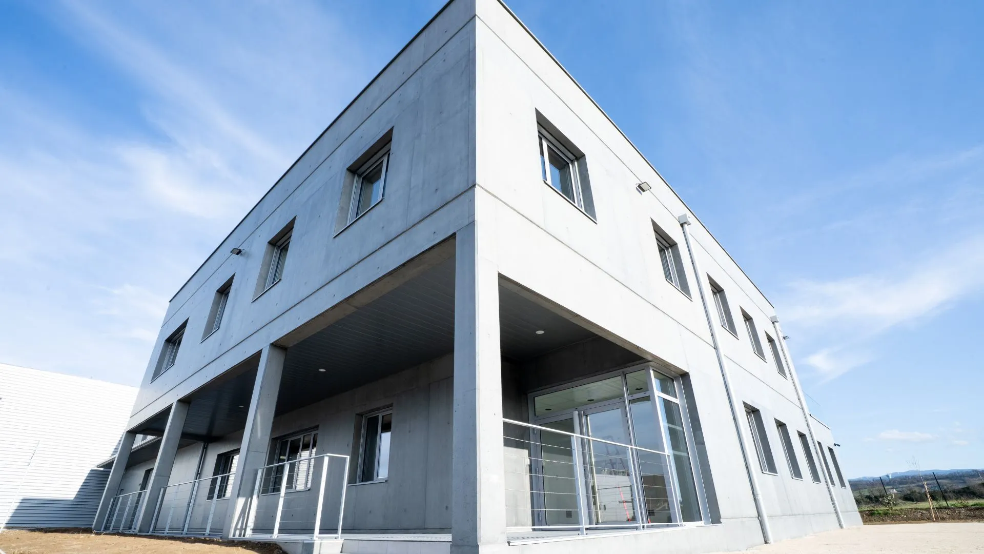 Façade du bâtiment terminé en béton avec entrée vitrée