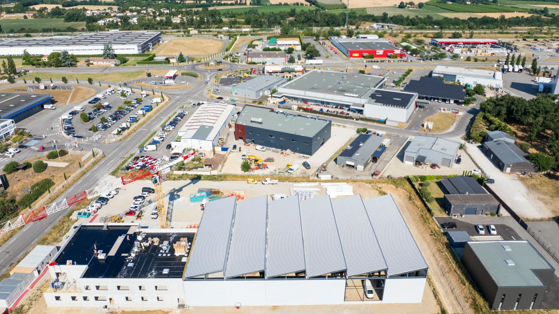 Vue aérienne du bâtiment achevé et de son parking dans la zone d'activités