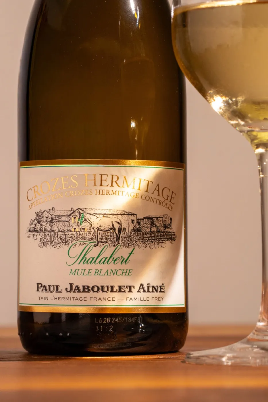 Bouteille de Crozes-Hermitage Thalabert, la lumière révèle le verre et la dorure de l'étiquette