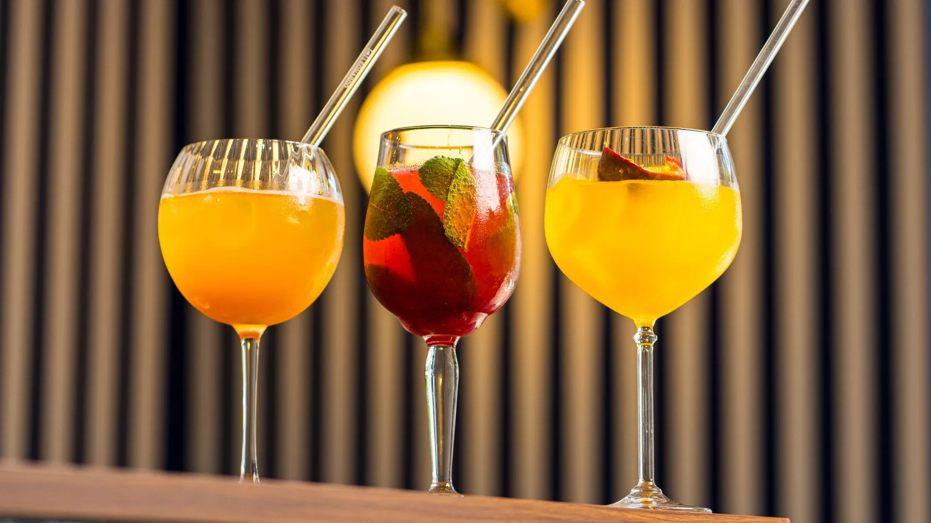 Trois cocktails colorés alignés sur un comptoir de bar