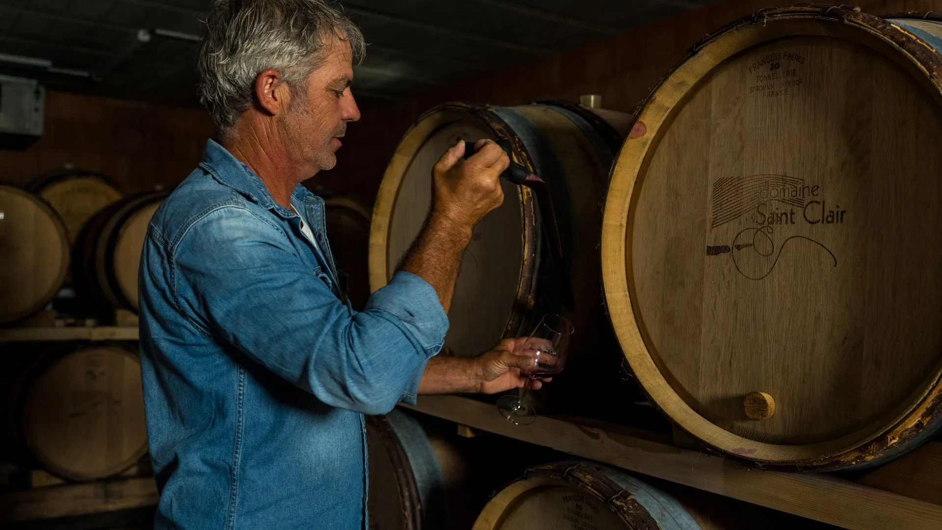 Vigneron prélevant le vin à la barrique dans son chai
