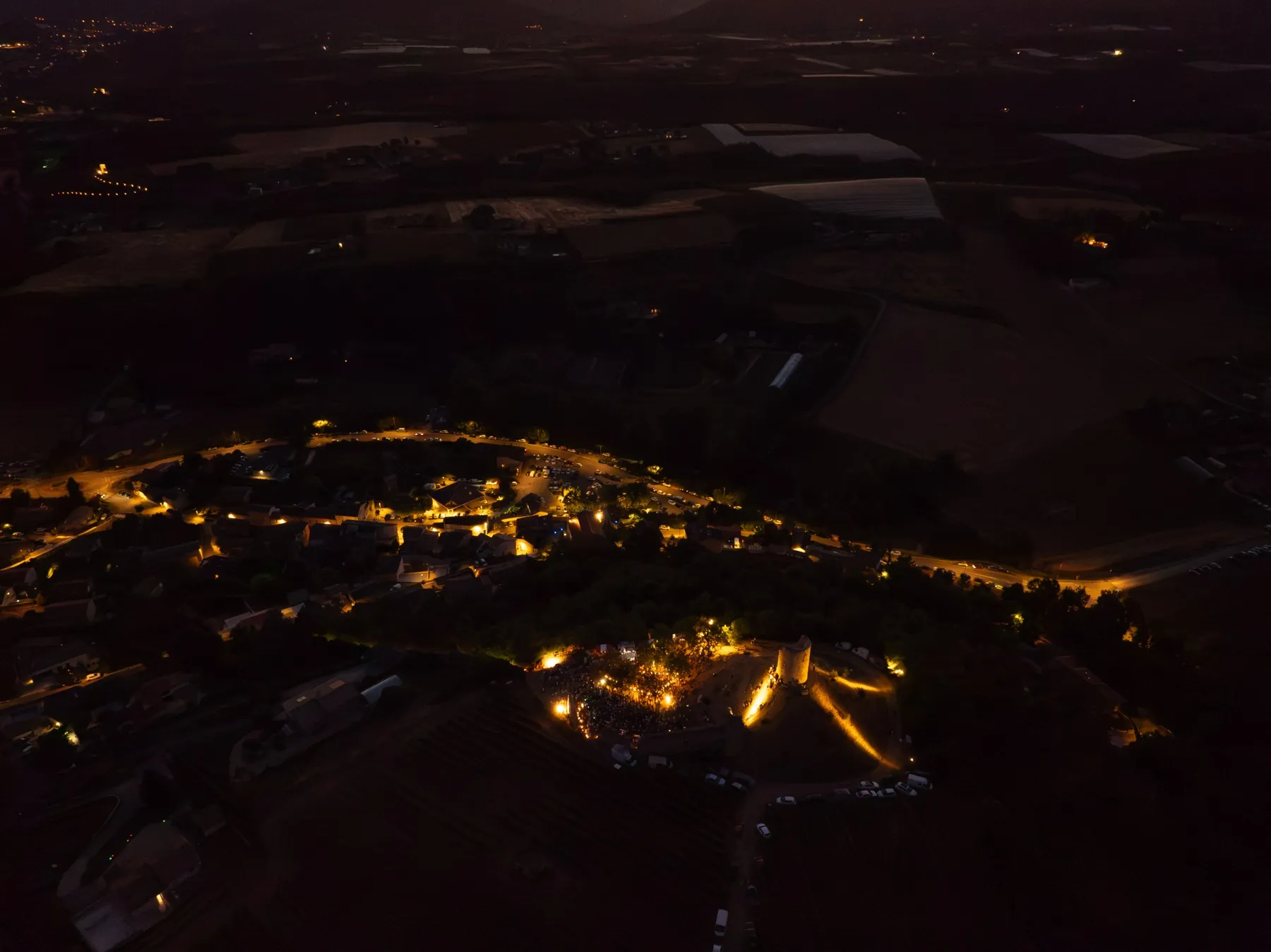 Le village et la butte illuminés de nuit, vus par drone