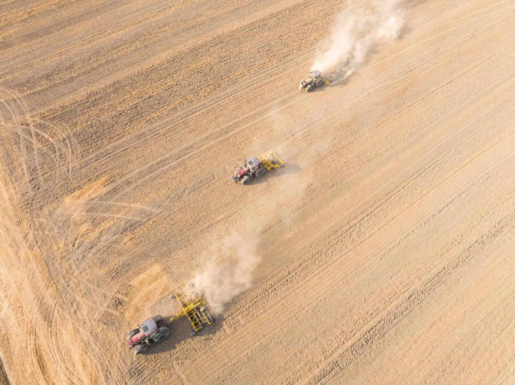 Vue aérienne à la verticale des trois tracteurs et de leurs panaches de poussière